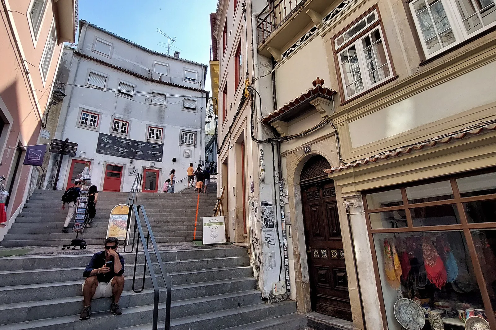 Visitors climb a flight of steps between tall tiled buildings on Rua de Quebra-Costas
